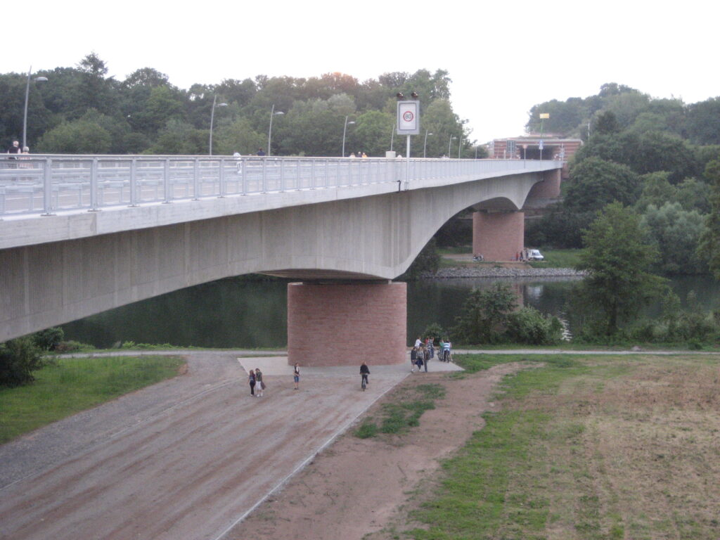 Eine moderne Brücke mit einer geschwungenen Betonstruktur, die über einen Fluss führt.