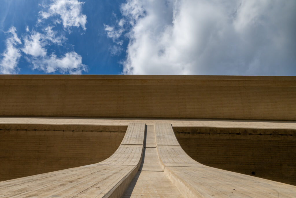 Architektonische Struktur mit geneigten Wänden und einem klaren Himmel im Hintergrund.