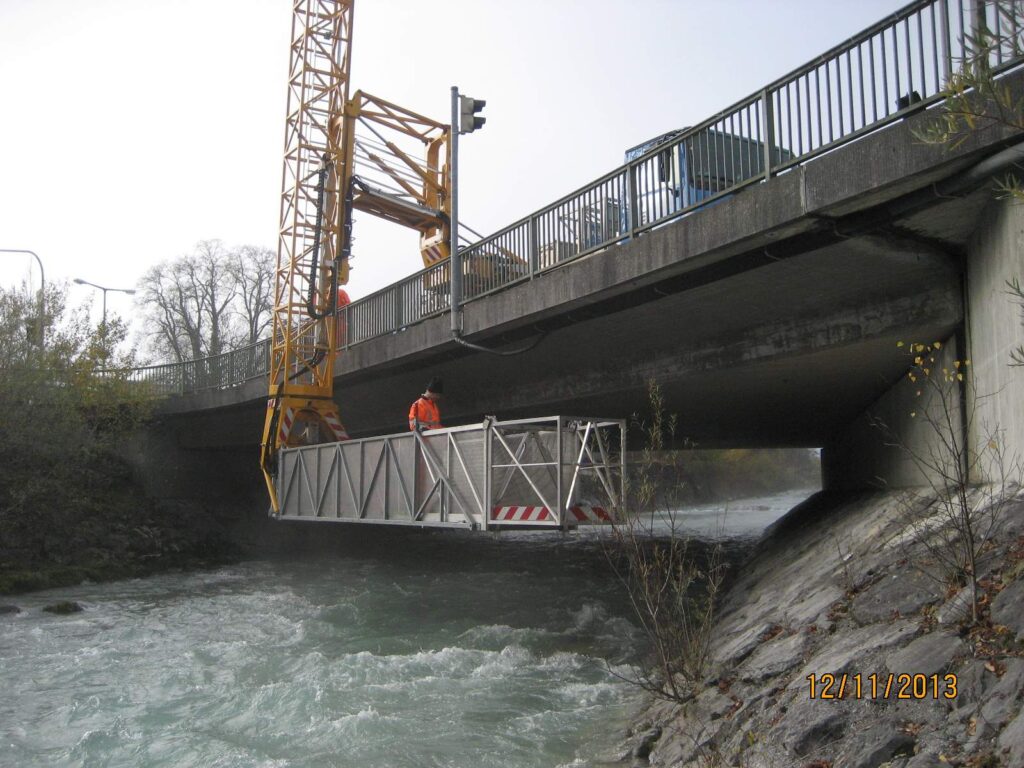 Brücke mit einem Kran, der eine Plattform über einen Fluss hebt.