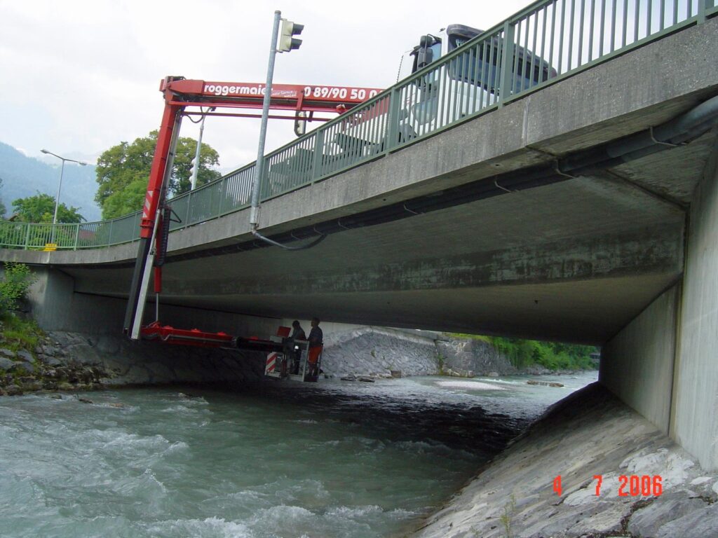 Brücke mit einem Kran, der über einen Fluss arbeitet, darunter sichtbar.