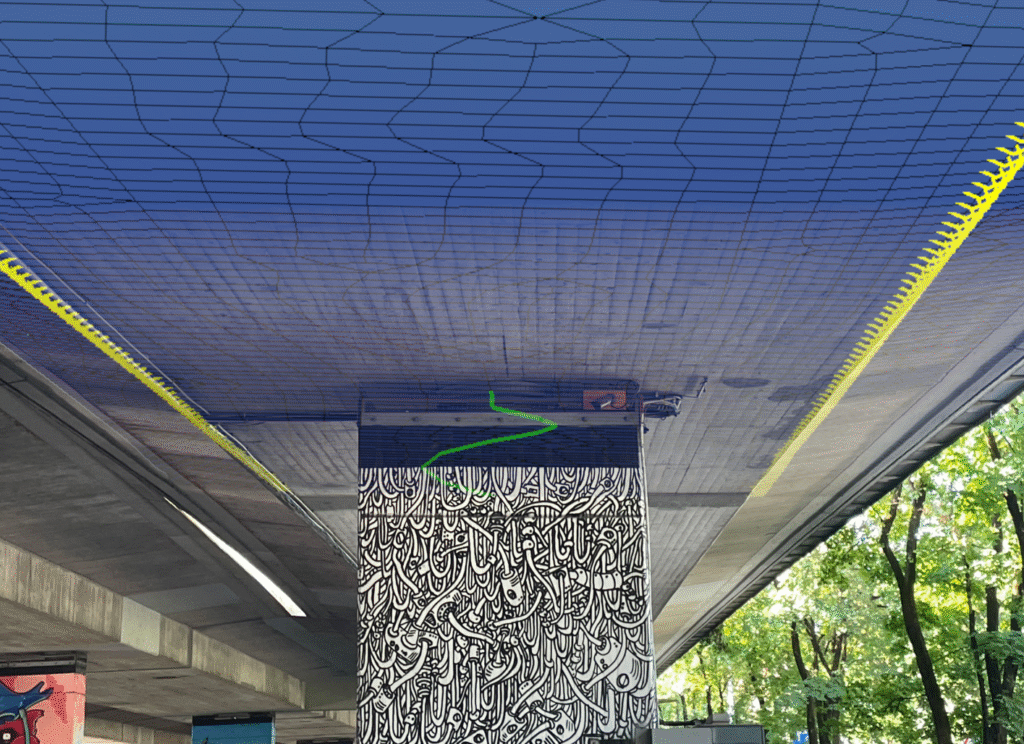 Graffiti an einer Säule unter einer Brücke mit geometrischen Mustern an der Decke.